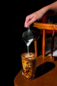 Cropped hand of woman holding drink on table