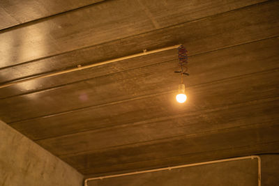 Low angle view of illuminated light bulbs hanging from ceiling