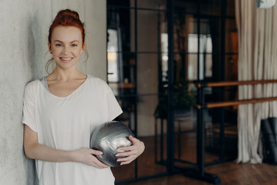 Portrait of smiling woman standing by wall