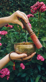 Close-up of hand holding metallic bowl against plants