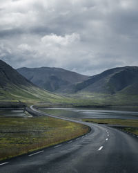 Scenic view of road by mountains against sky