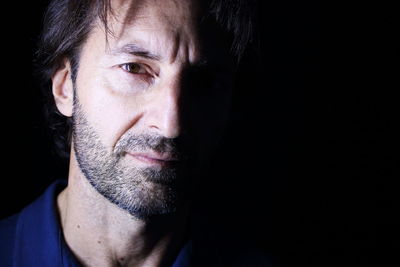 Close-up portrait of man against black background