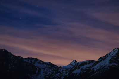 Scenic view of snowcapped mountains against sky at sunset