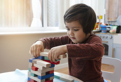 Cute boy playing block removal game at home