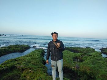 Portrait of young man standing in sea against clear sky