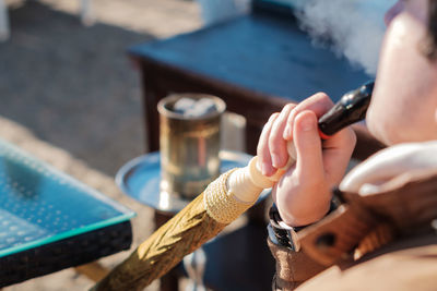 Person smoking water pipe while sitting outdoors