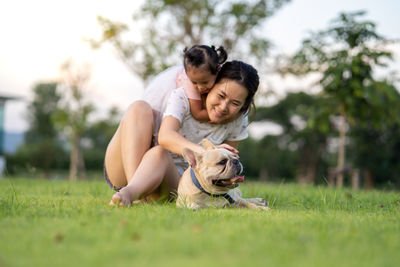 Smiling woman with daughter touching dog in park