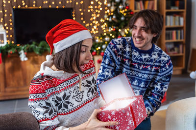 Pretty young woman surprisedly receives a christmas gift box from her boyfriend