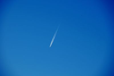 Low angle view of vapor trail against clear blue sky