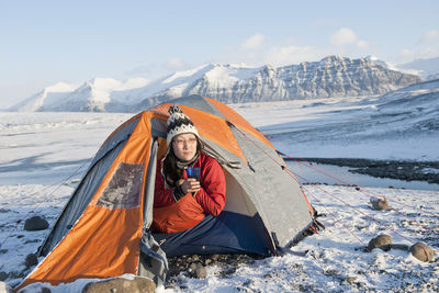 Woman drinking hot beverage at winter camp in iceland