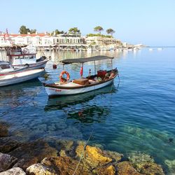 Boats moored in sea against clear sky