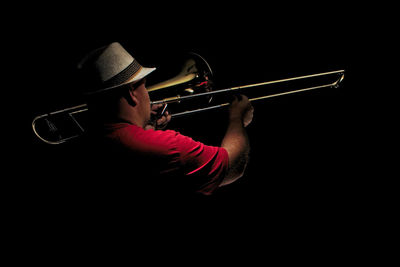 Man playing trumpet against black background