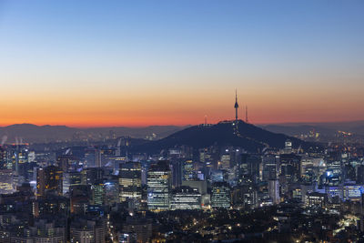 Illuminated buildings in city against sky during sunset