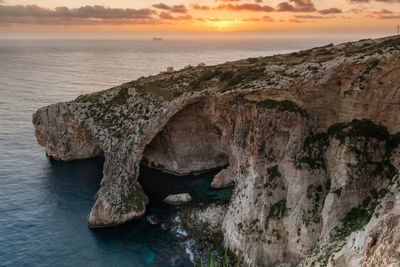 Rock formation in sea against sky during sunset