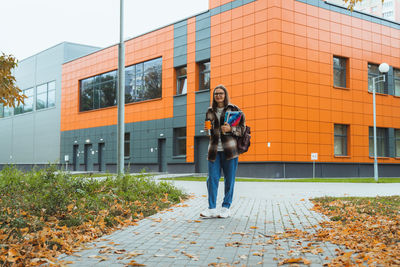 Full length portrait of woman standing against building