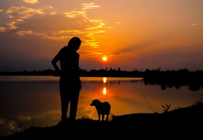 Silhouette man standing by sea against sky during sunset