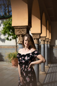 Portrait of smiling young woman standing against built structure