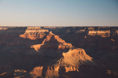 Scenic view of eroded landscape against clear sky during sunset