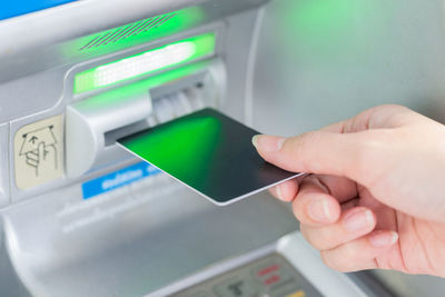 Cropped hand of woman using atm