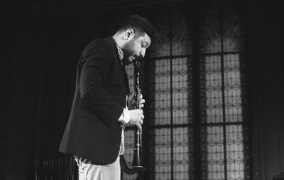 Man playing clarinet while standing at studio