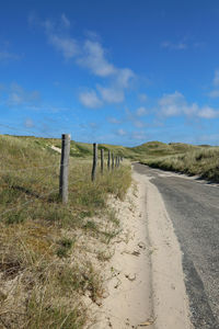 Road by landscape against blue sky