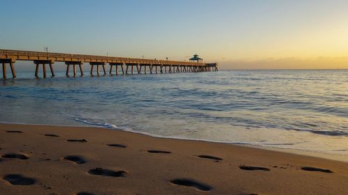 Scenic view of beach against clear sky during sunset