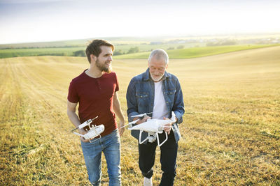 Senior father and his adult son with drone on a field