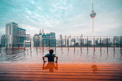 Rear view of man looking at city buildings against sky