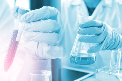 Double exposure of scientist hands holding chemicals in laboratory glassware