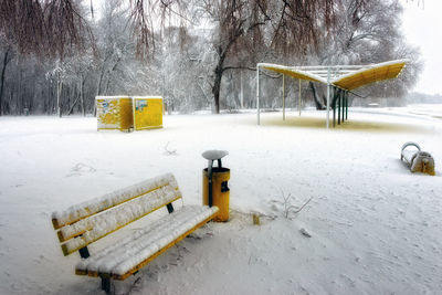 Snow covered field against trees