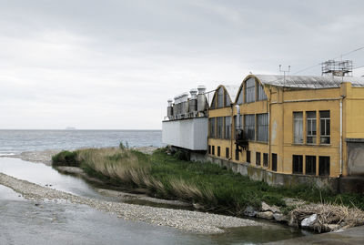 Built structure on beach by sea against sky