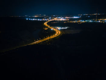 Illuminated city by river against sky at night