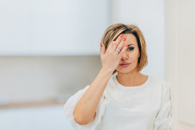 A beautiful woman in a white t-shirt preens for a date, straightens her hair, hair. mock-up. closeup