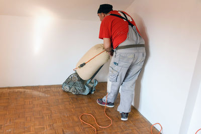 Man sanding hardwood floor with grinding machine