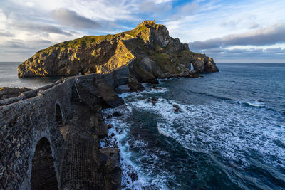 Rock formation on sea shore against sky