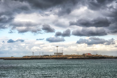 View of buildings and sea against cloudy sky