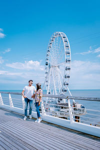 People on ferris wheel by sea against sky