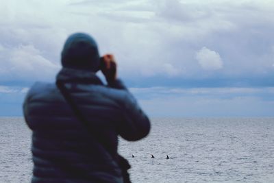 Rear view of man on beach against sky