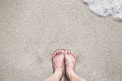 Low section of person standing on sand