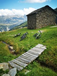 House on field by mountain against sky