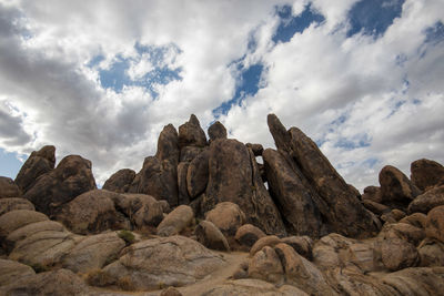 Low angle view of rocks against sky in desert landscape with clouds