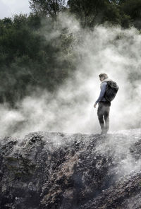 Man standing by waterfall in forest