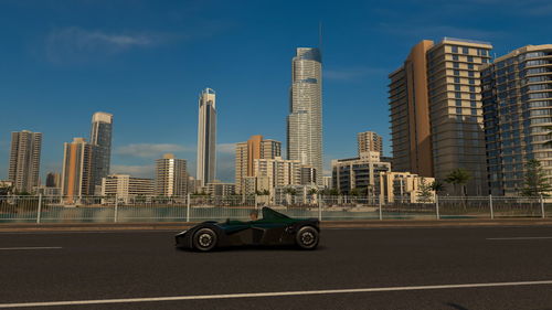 Cars on road by buildings against sky in city