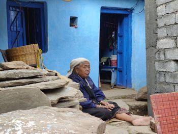 Side view of young women sitting on wall