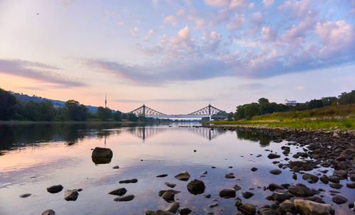 Bridge over river against sky at sunset