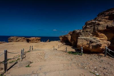 Rocks on beach against clear blue sky