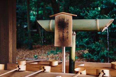 Close-up of cross on table against trees