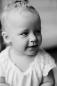 Cute baby girl smiling while looking away at home