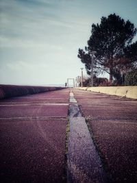 Surface level of road amidst field against sky