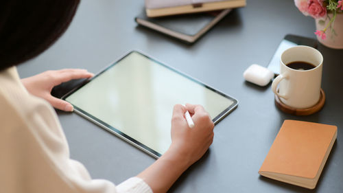 Midsection of person using mobile phone on table